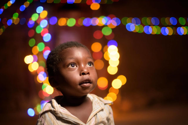 Zambian girl looking up with Christmas lights in background.