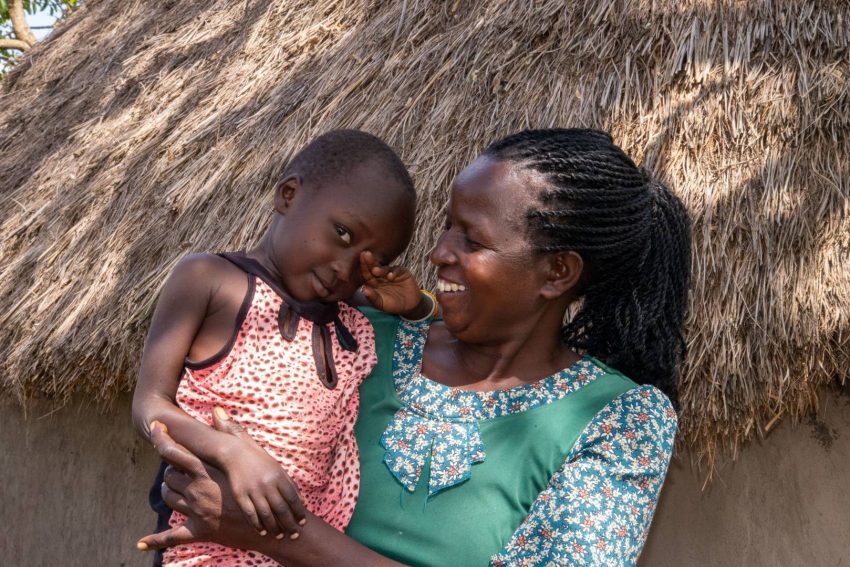Akanya holds her granddaughter Delilah at their home in Uganda. Last year Delilah contracted malaria, and a World Vision-trained community health worker was able to diagnose her and provide anti-malarial medicine that healed her.
